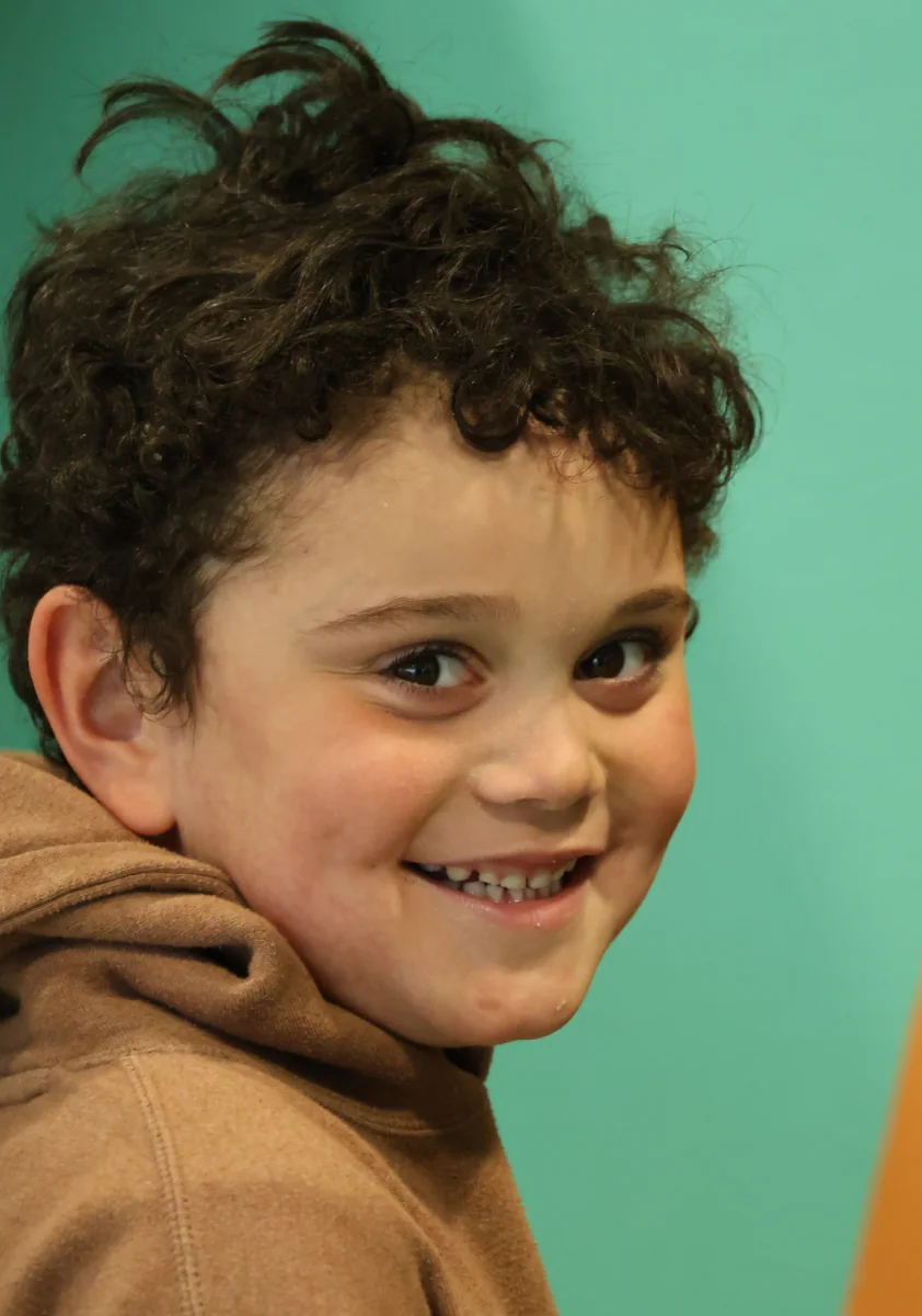 A happy child smiling against a green background.