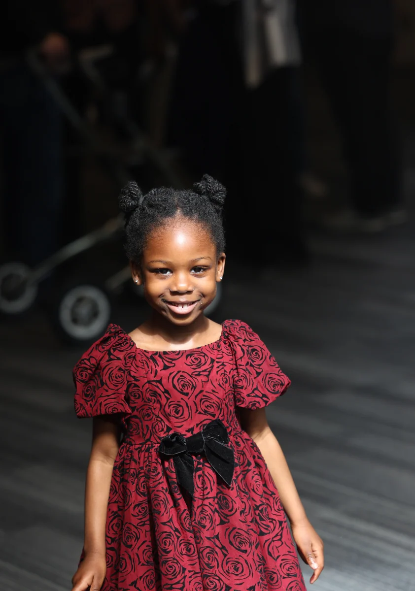 A little girl in a red dress smiling.