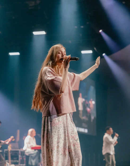 A woman singing on stage during worship at Northshore Church.