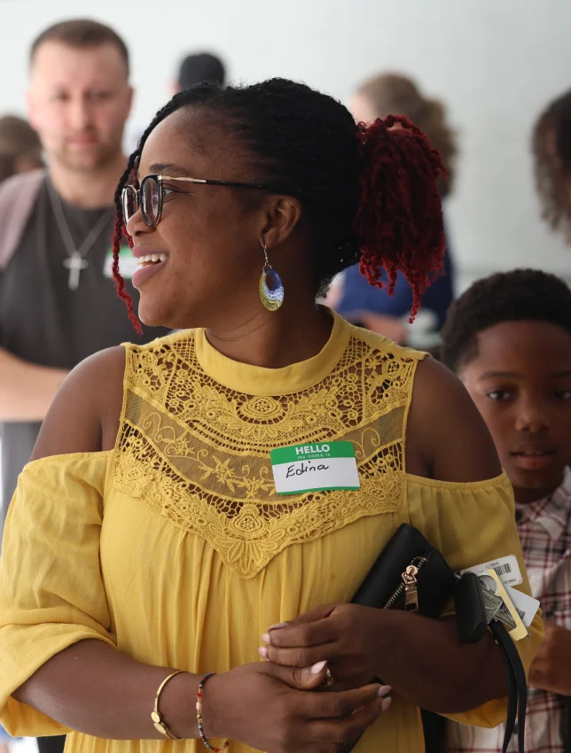 A woman in a yellow dress smiling at a Connect event.