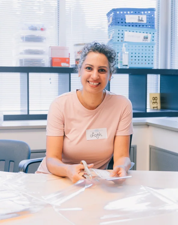 A woman cutting plastic material at a desk while volunteering.