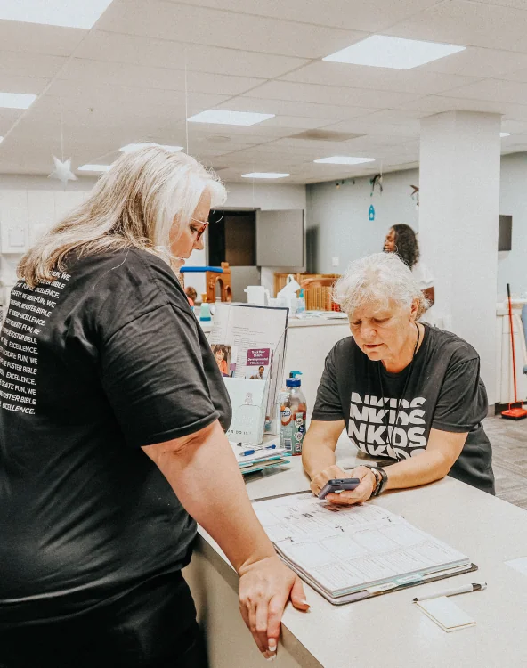 Two women discussing details at a counter while serving.