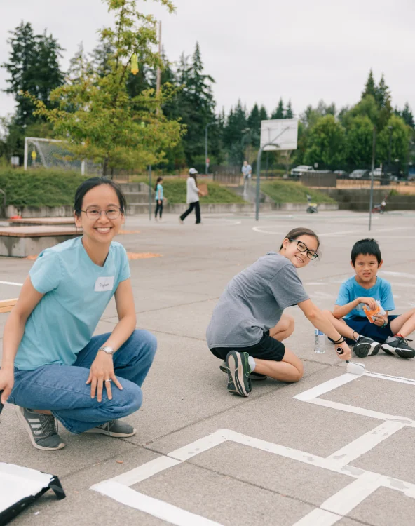 Children painting a school sport court while volunteering.