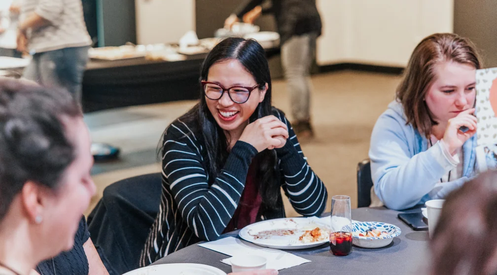 Women laughing around a dinner table at MomCo.