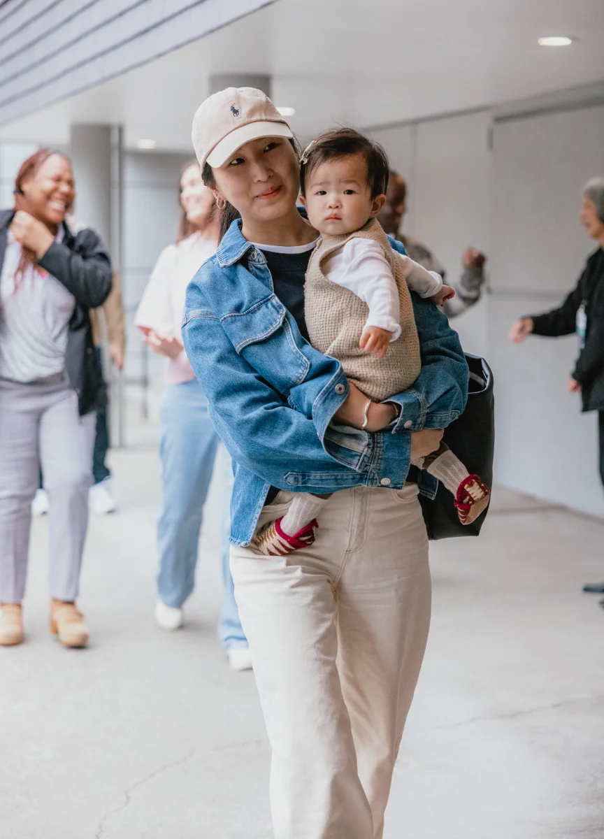 A mother holding her baby outdoors.