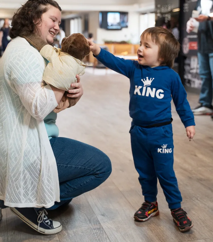 A women holding one kid and talking to another.