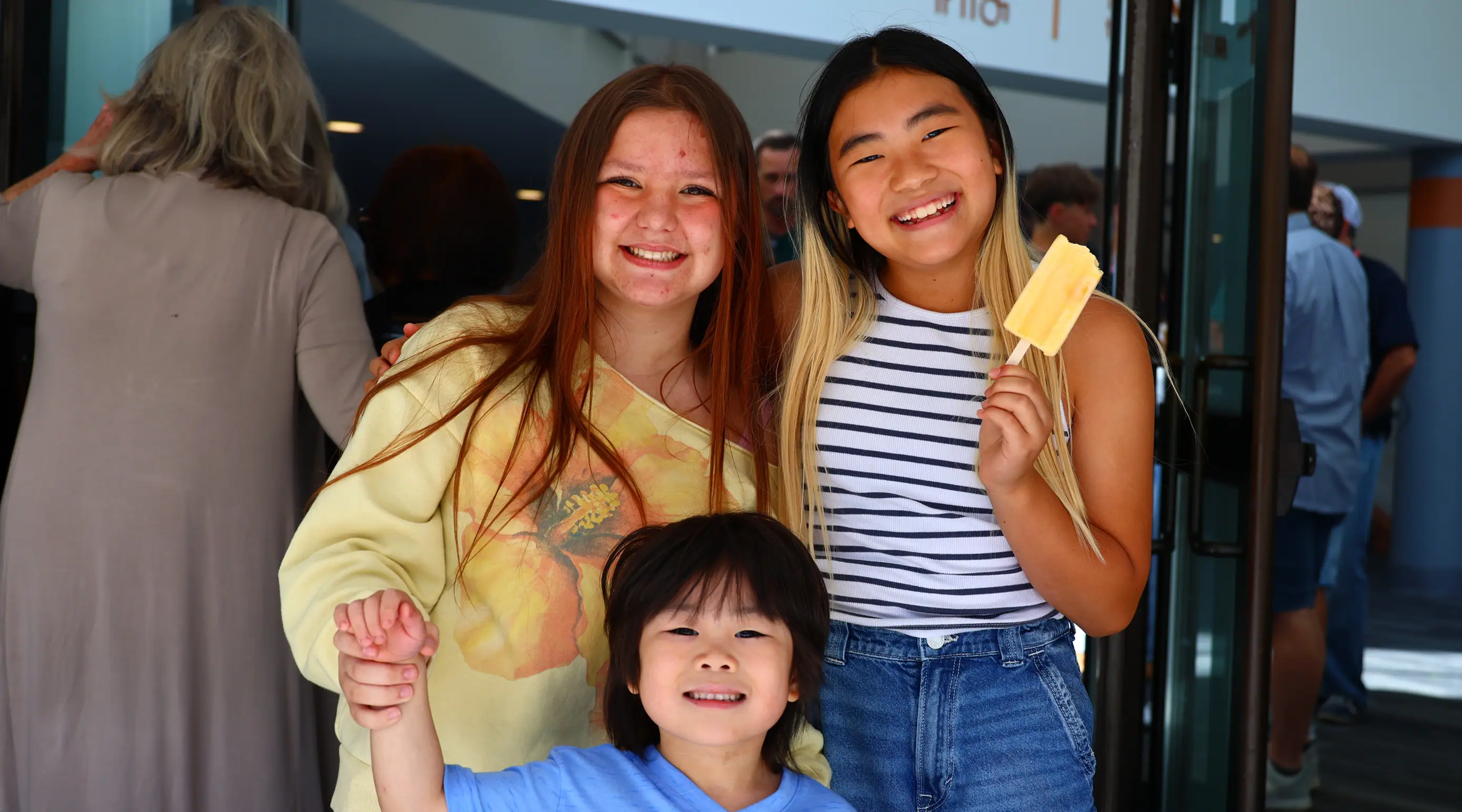 Three children smiling while eating popsicles.