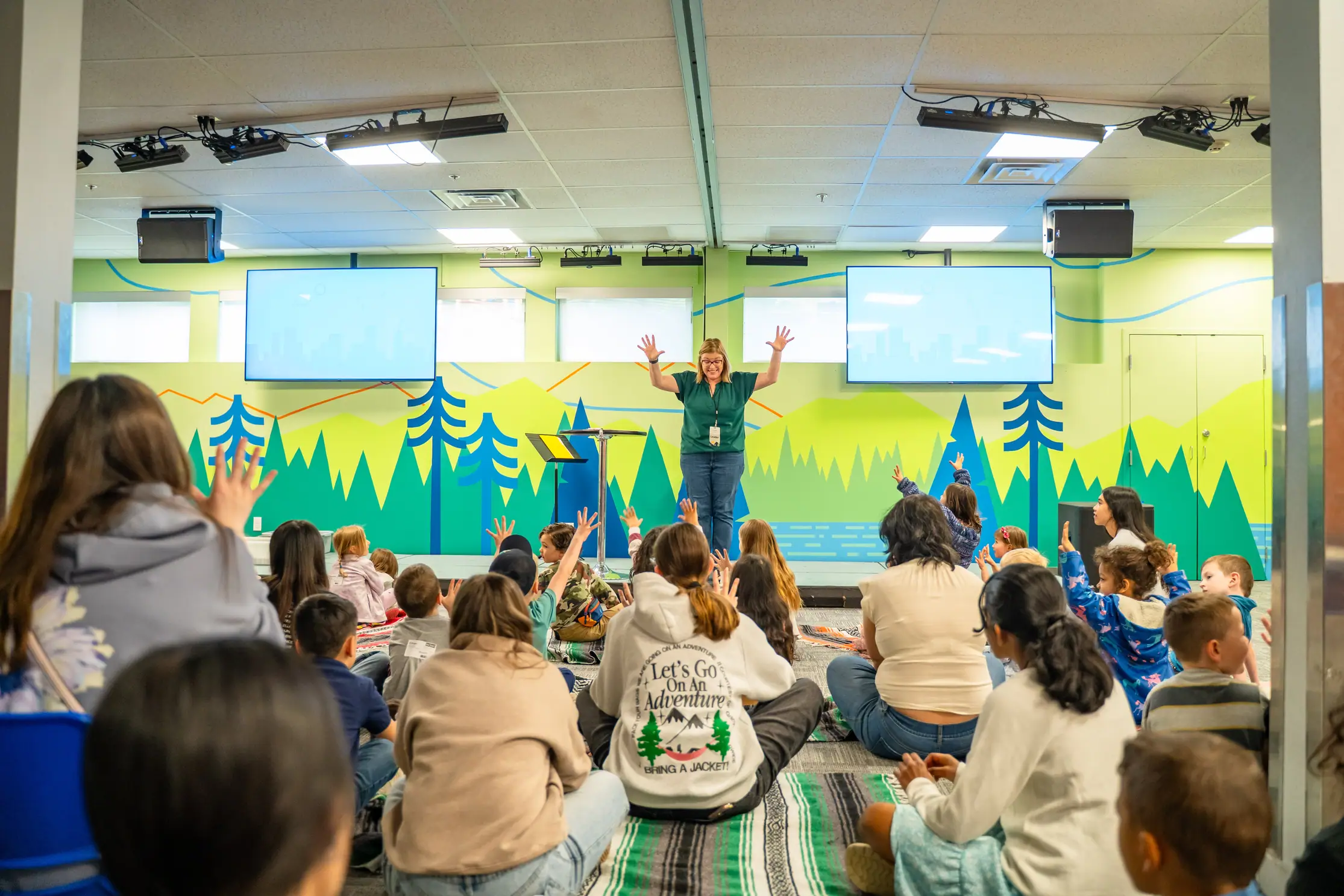 Children sitting and listening to a presenter in a classroom.