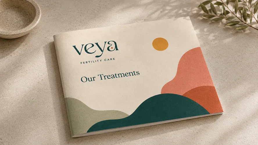 The Veya Fertility 'Our Treatments' brochure resting on a pale stone surface.