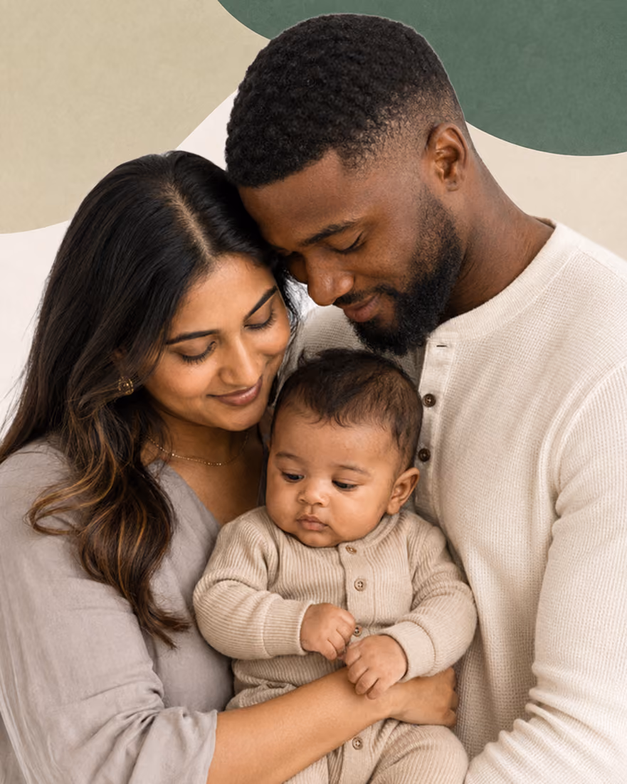 A couple holding their baby, their heads resting together.
