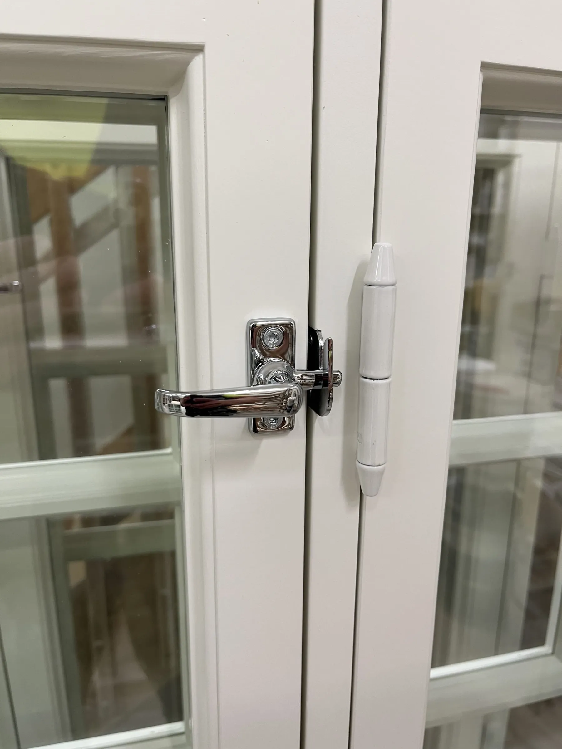 Valkoisen perinneoven kromattu painike ja sarana läheltä kuvattuna.