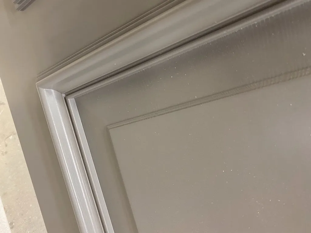 Lähikuva harmaaksi maalatun välioven profiloidusta puupinnasta.
