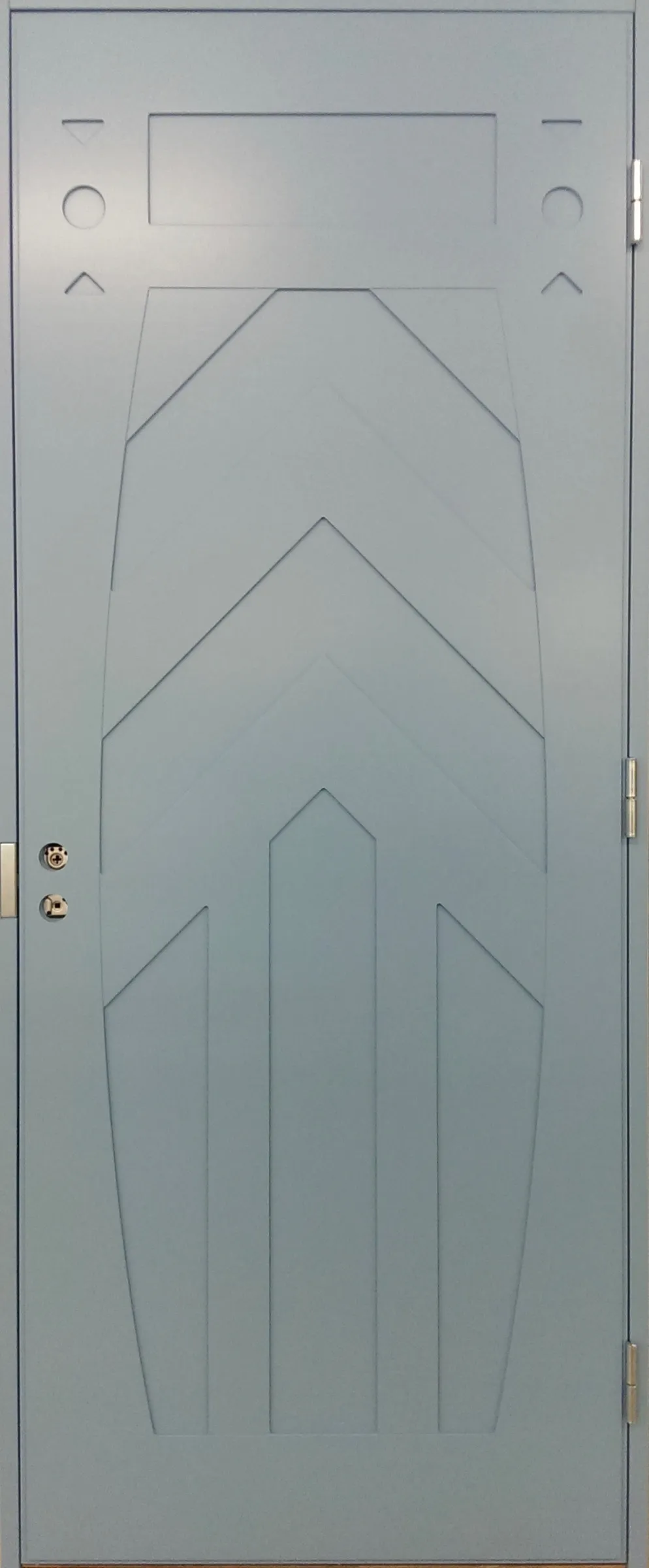 Vaaleansininen ulkoovi, jossa on geometrisiä urakuvioita ja nykyaikainen muotoilu.