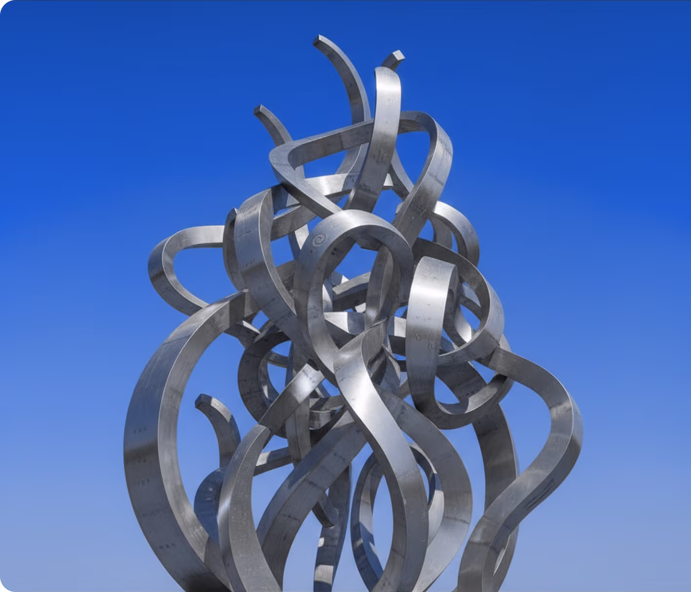 Curved silver metal loops entwined in a complex abstract sculpture against blue sky.