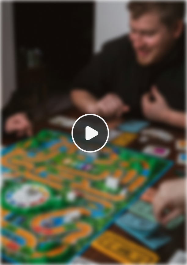 People playing a colorful board game around a table with dice and cards.