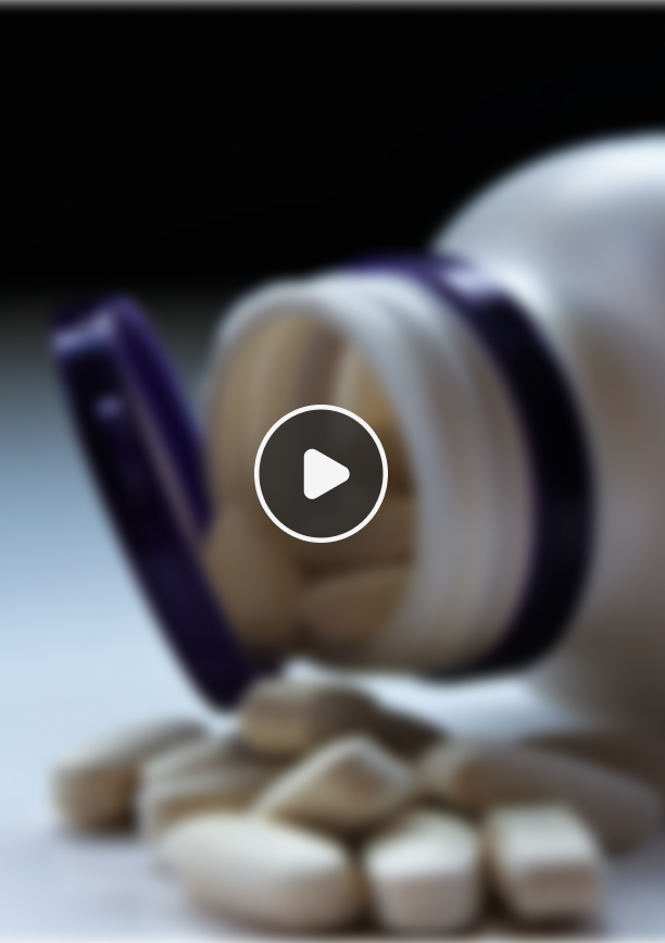 White pill capsules spilling out of an open white bottle with a purple cap on a surface.