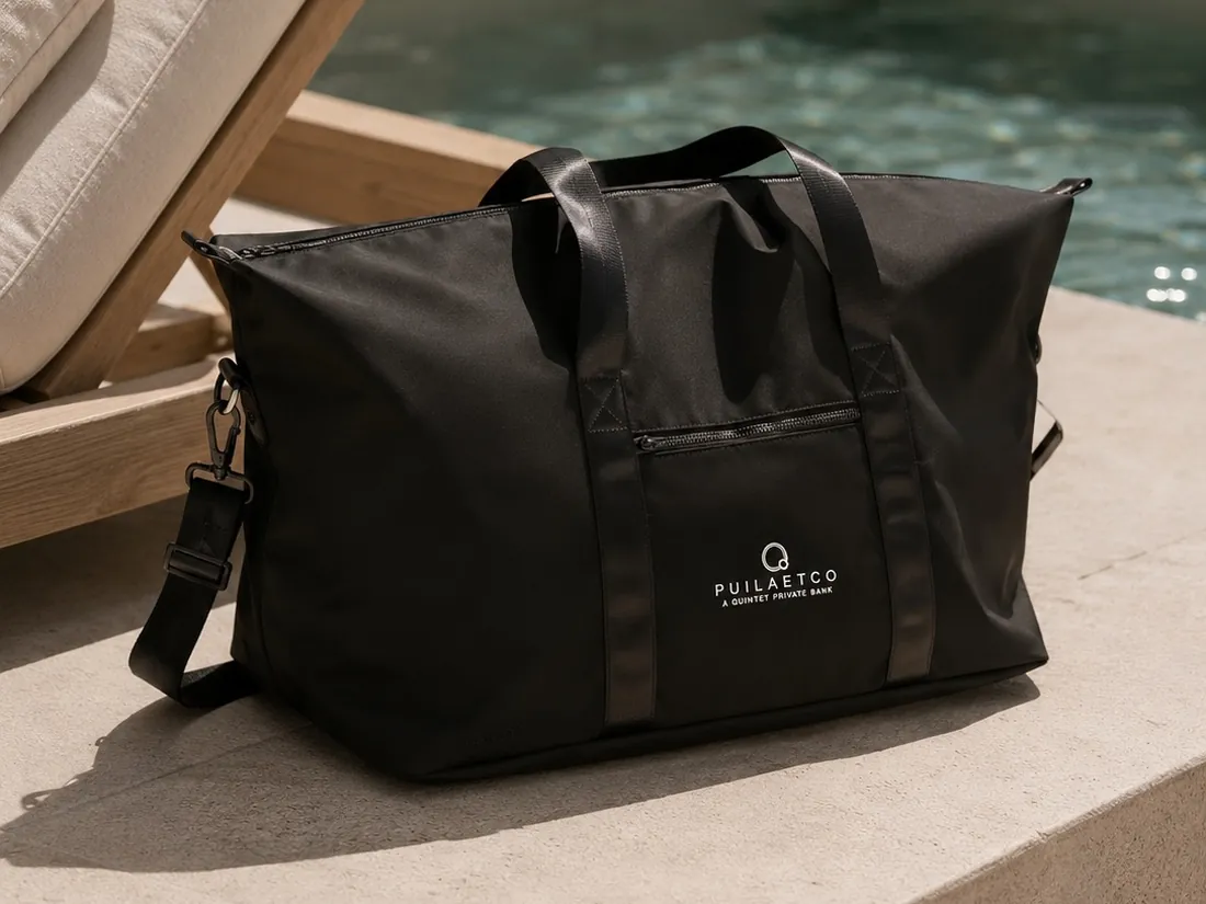 Sac de week-end noir marqué du logo Puilaetco, posé au bord d’une piscine