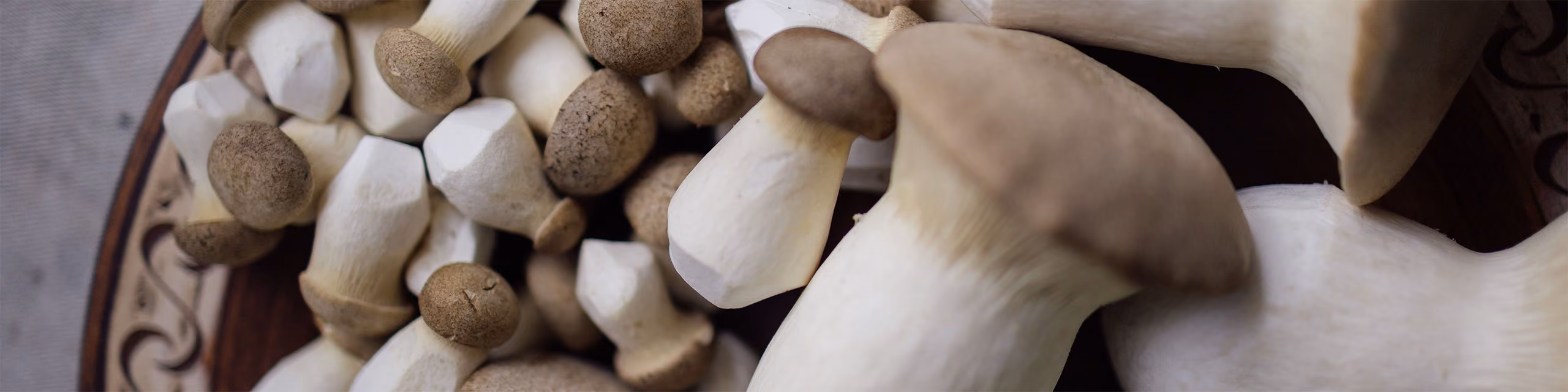 Close-up of fresh brown and white king oyster mushrooms piled on a decorative plate.
