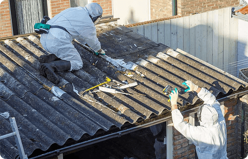 Technicians removing asbestos roofing on a home
