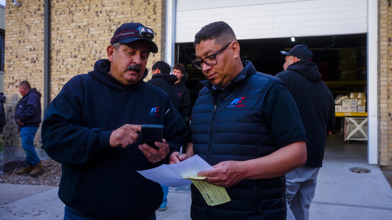 Two AmeriForce technicians reviewing paperwork outside the shop