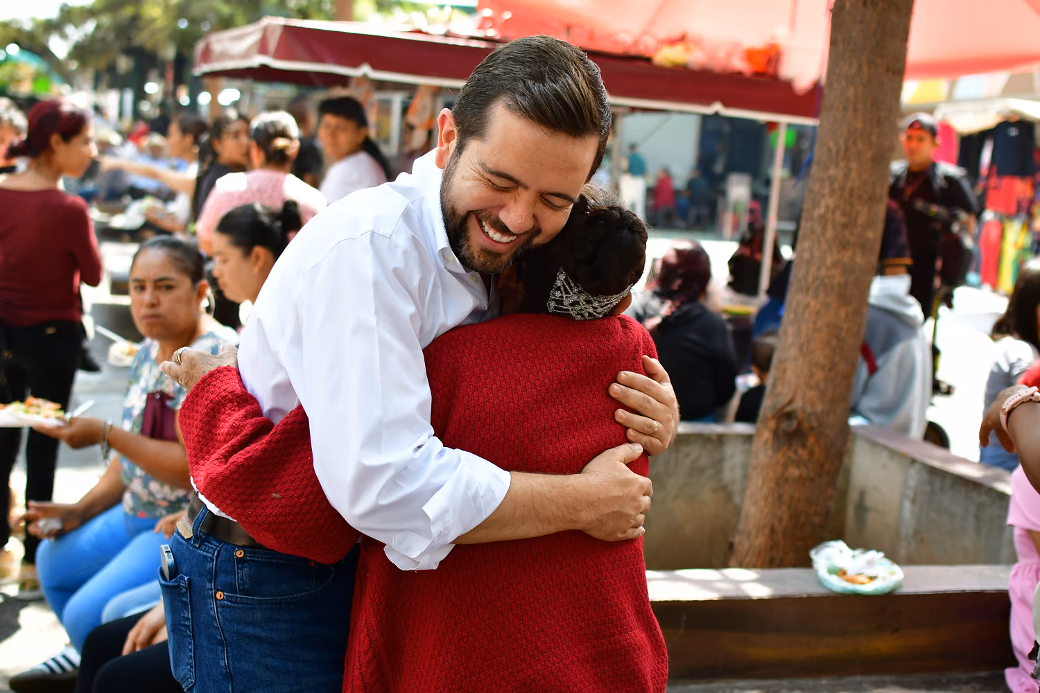 Smiling woman in pink shirt talks with man in blue denim shirt in a casual setting.