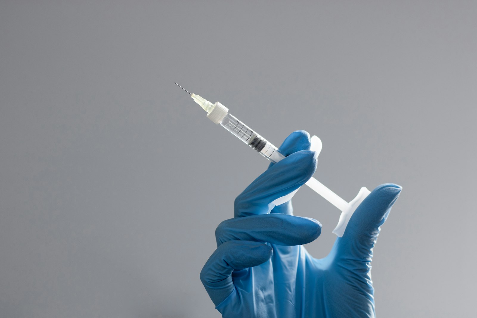 Gloved hand holding a syringe