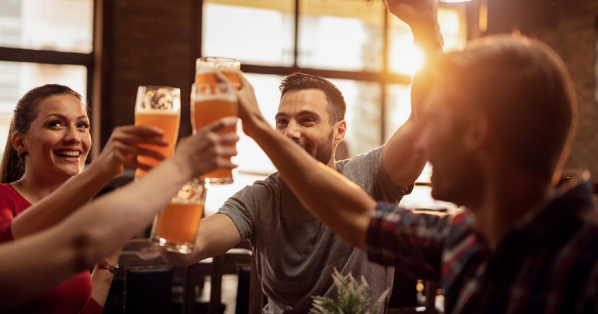 Grupo de jovens felizes brindando em bar. Programação pós-Carnaval para bares e restaurantes
