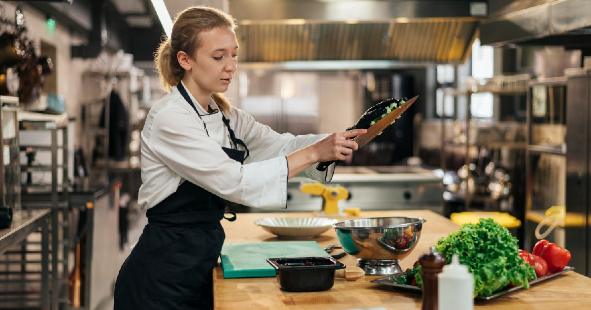 chef feminina com avental cozinhando na cozinha. Sistema KDS Zig: organize pedidos e ganhe eficiência na cozinha