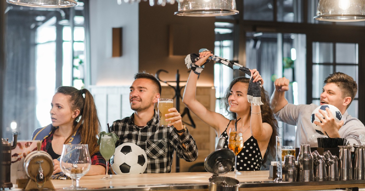 homens e mulheres vendo jogo em bar -Guia prático para preparar o bar para jogos de futebol