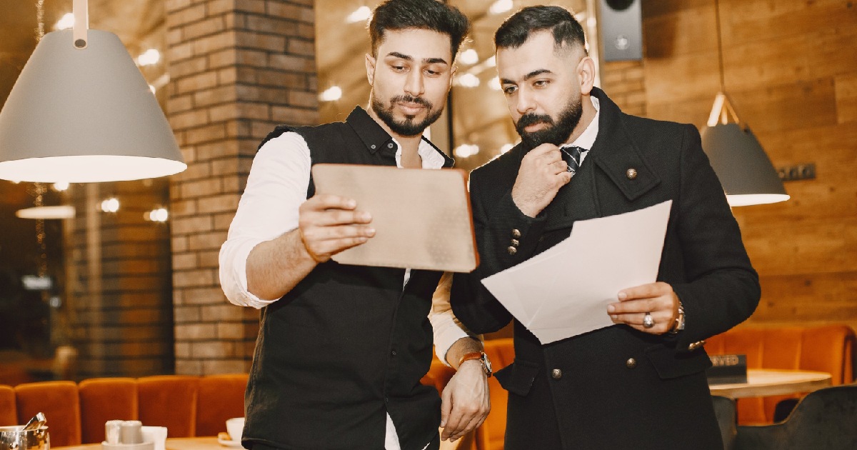 Homens olhando documentos em restaurante - planejamento anual de eventos para bar ou restaurante