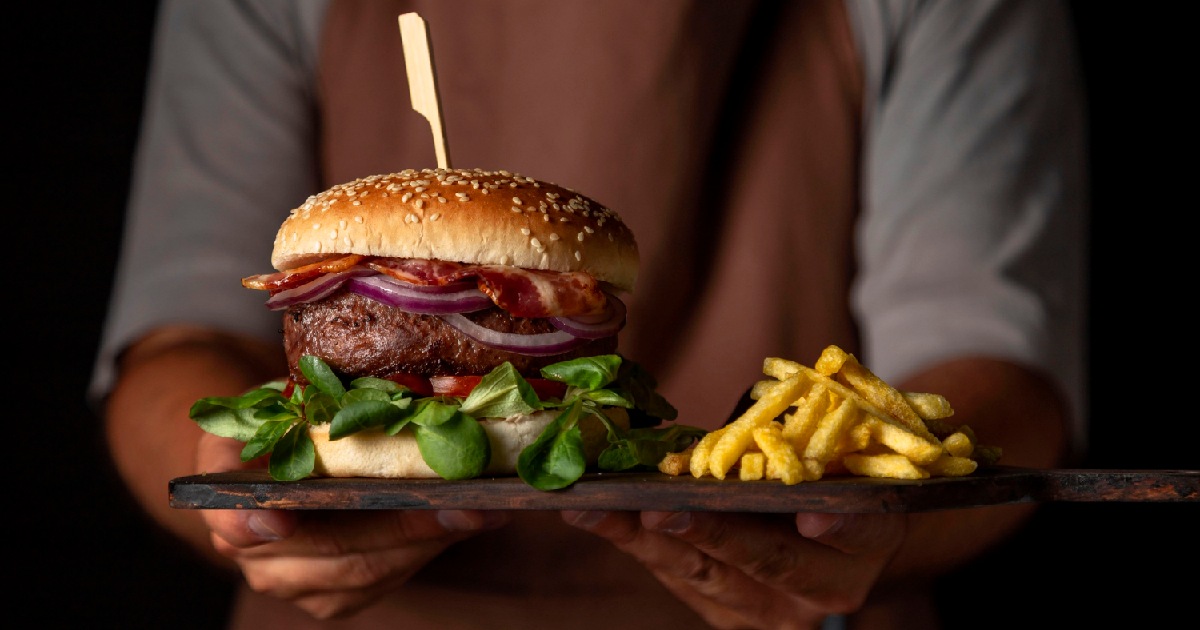 Garçom servindo porção de batatas com hambúrguer - escolha o melhor Sistema para hamburgueria