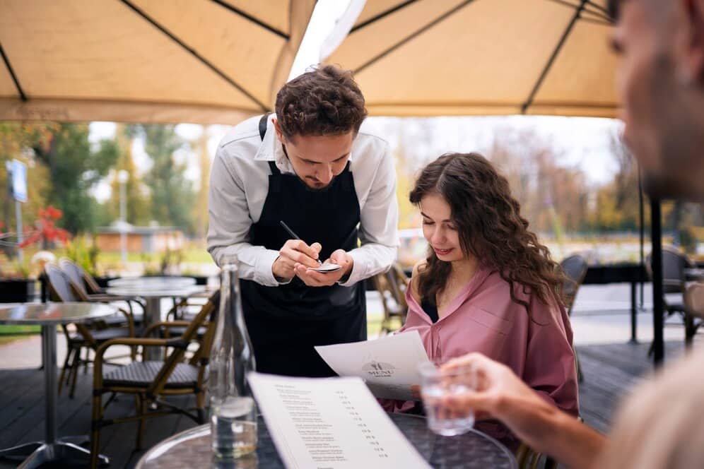 Garçom em atendimento a mulher. Como gerenciar lista de espera em restaurantes