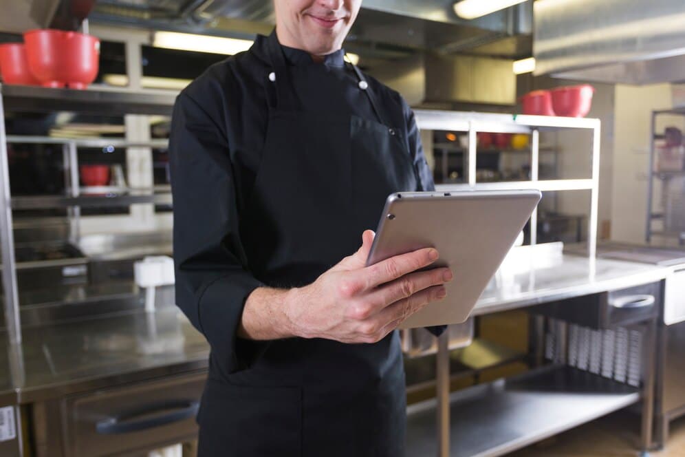 Chef com um tablet realizando a gestão de estoque