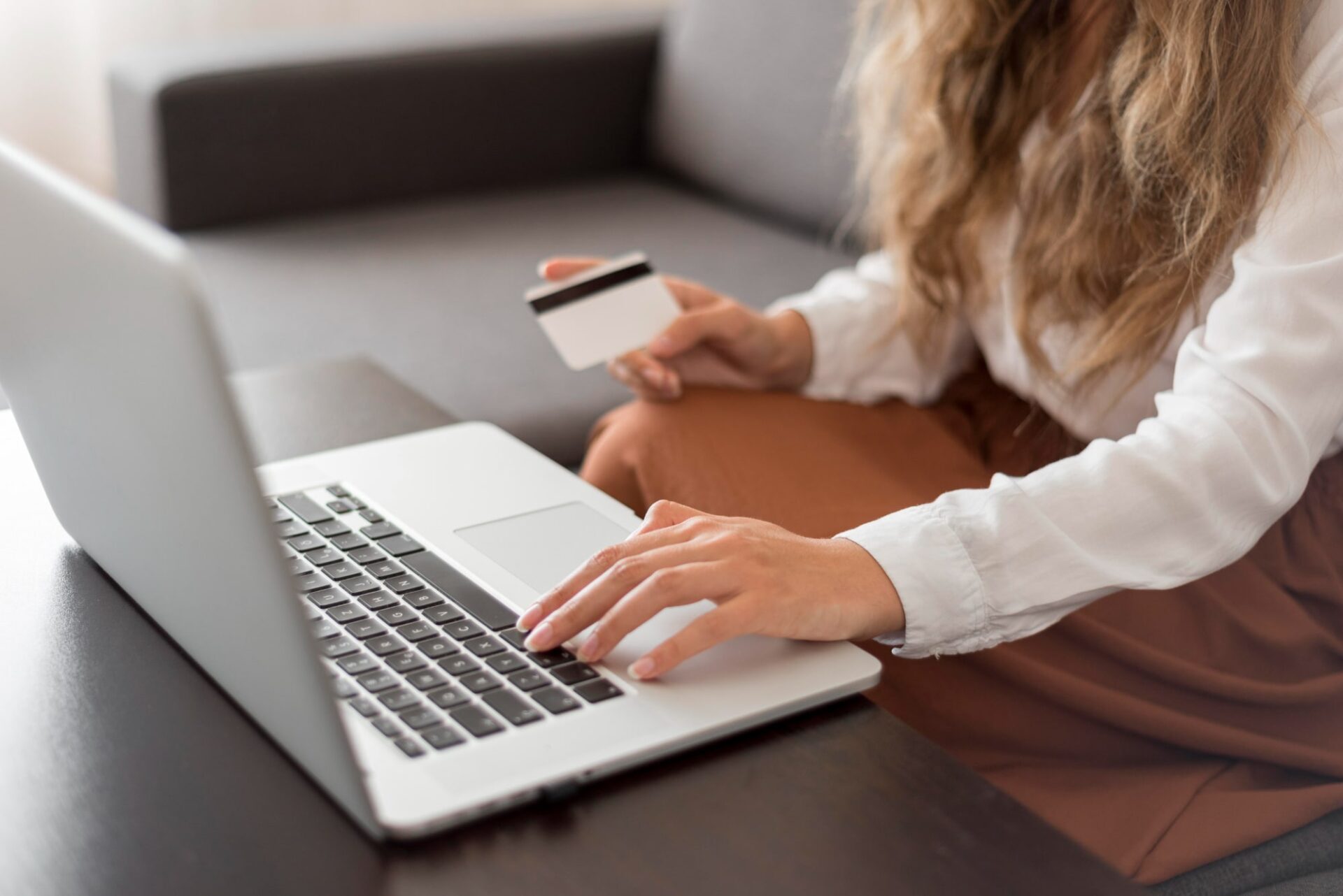 mulher segurando cartão em frente ao pc Como escolher a melhor - plataforma para venda de ingressos online