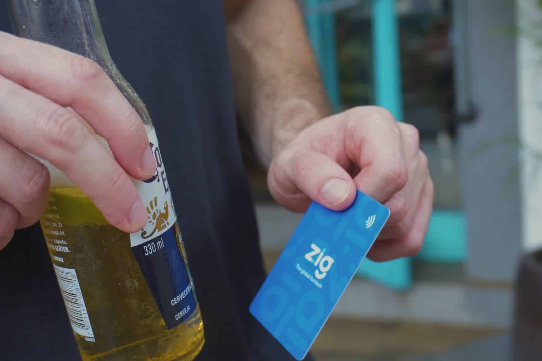 Pessoa segurando cerveja e cartão zig_ Personalizando ofertas com dados coletados via cashless pré-pago