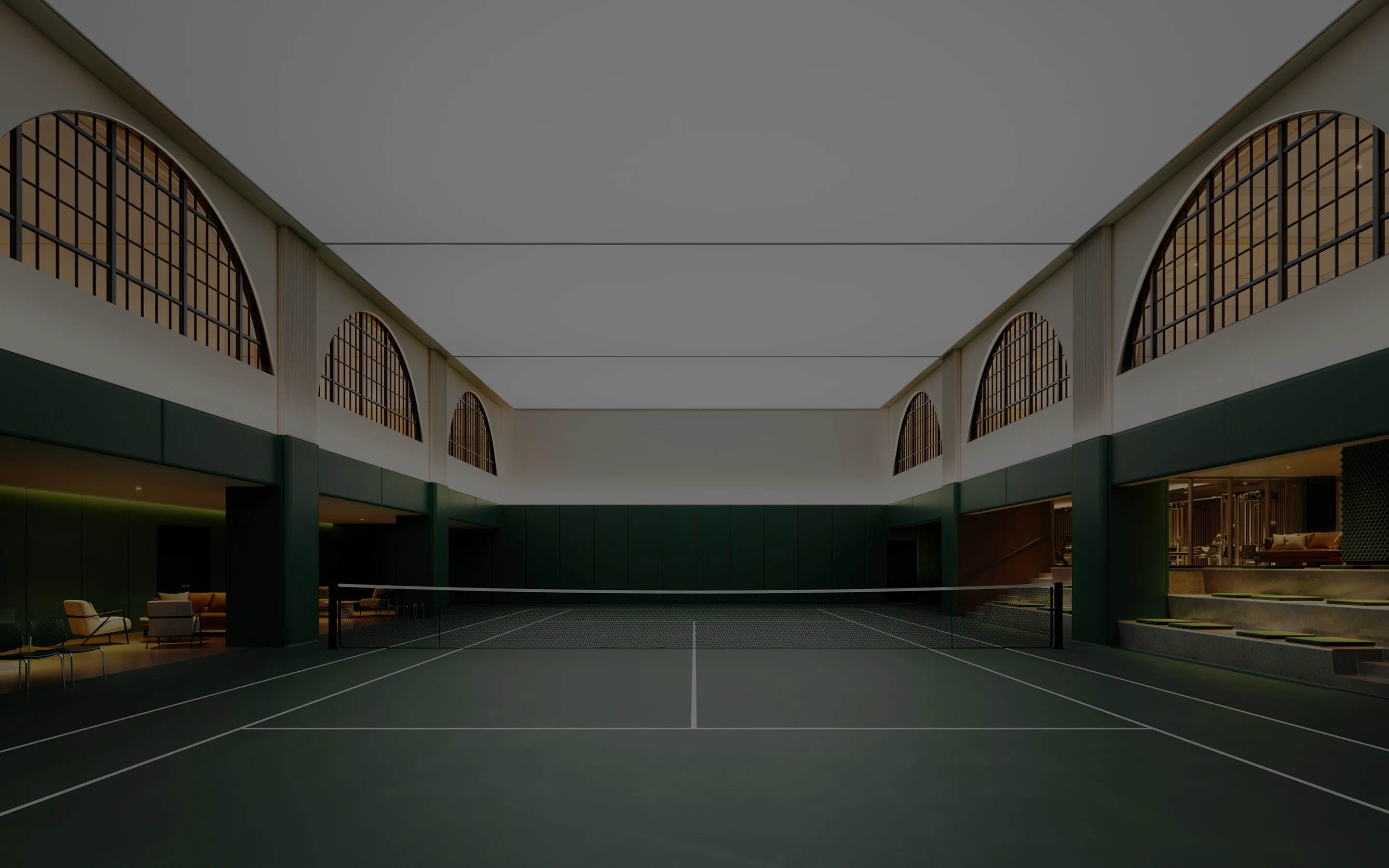 Indoor tennis court at Kings Athletic Club, framed by arched windows, dark green walls, lounge seating, and tiered spectator benches.