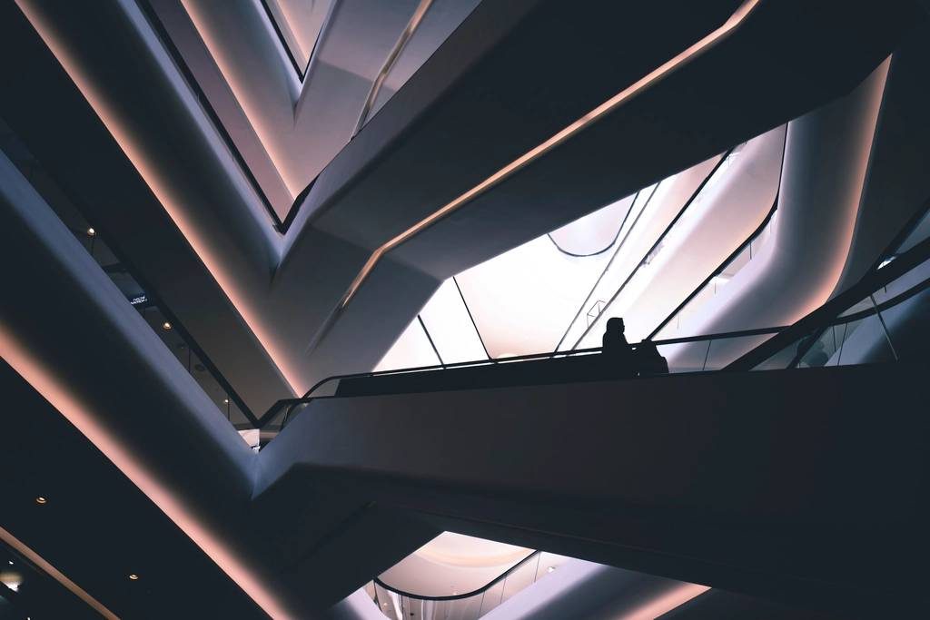 Silhouettes of people on an escalator in a shopping mall