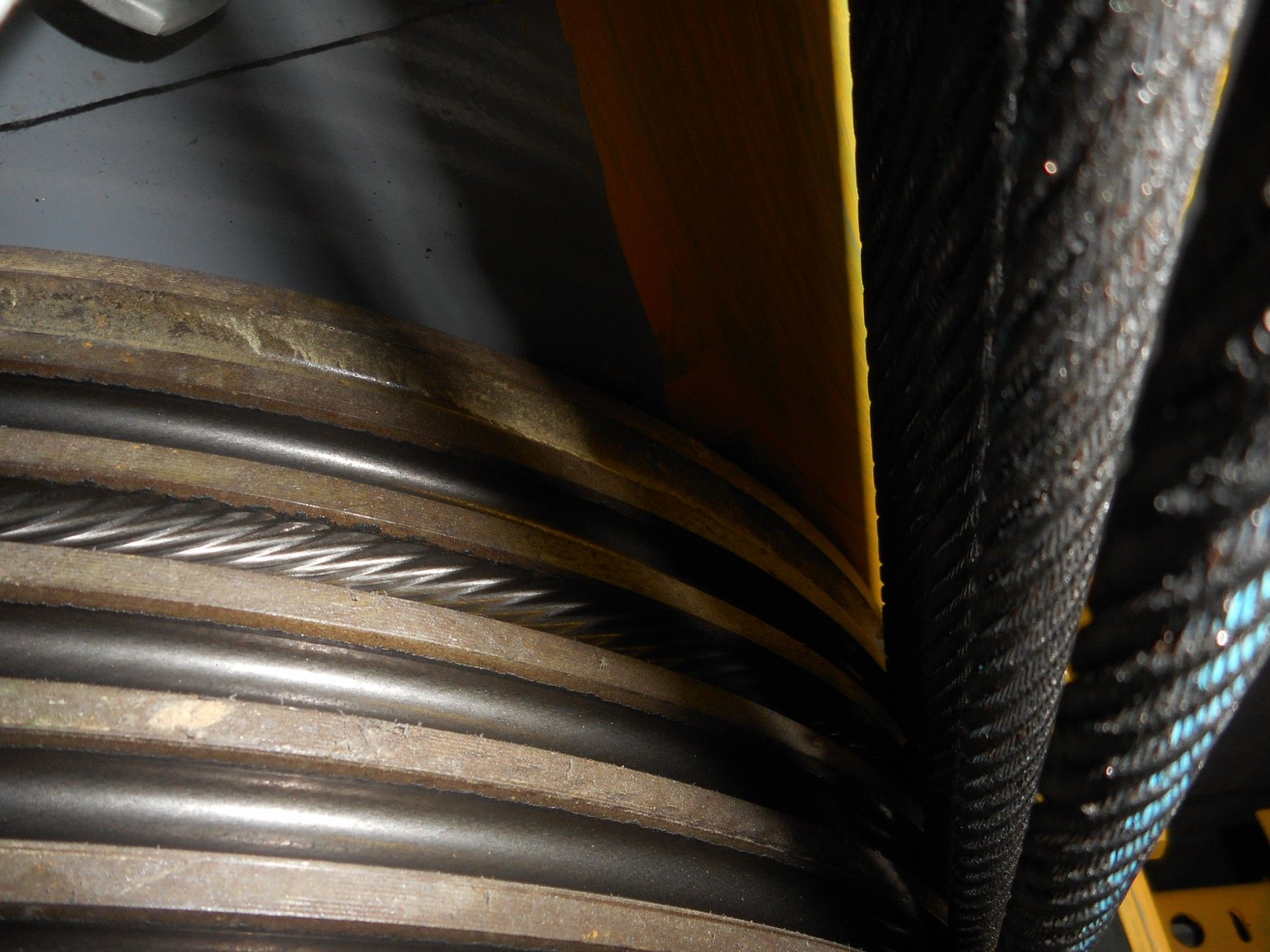 Close-up of worn grooves on a lift traction sheave, with the hoist ropes running over it