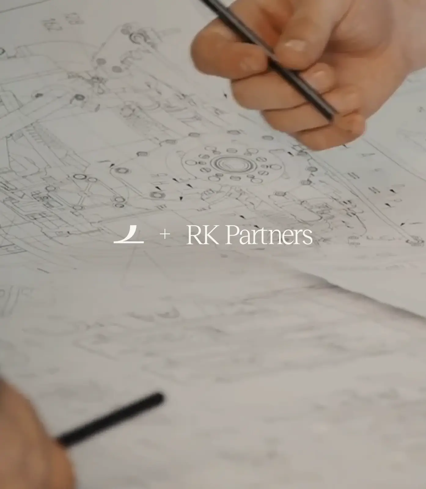 Hand holding a pen over detailed technical drawings with text 'RK Partners' centered.