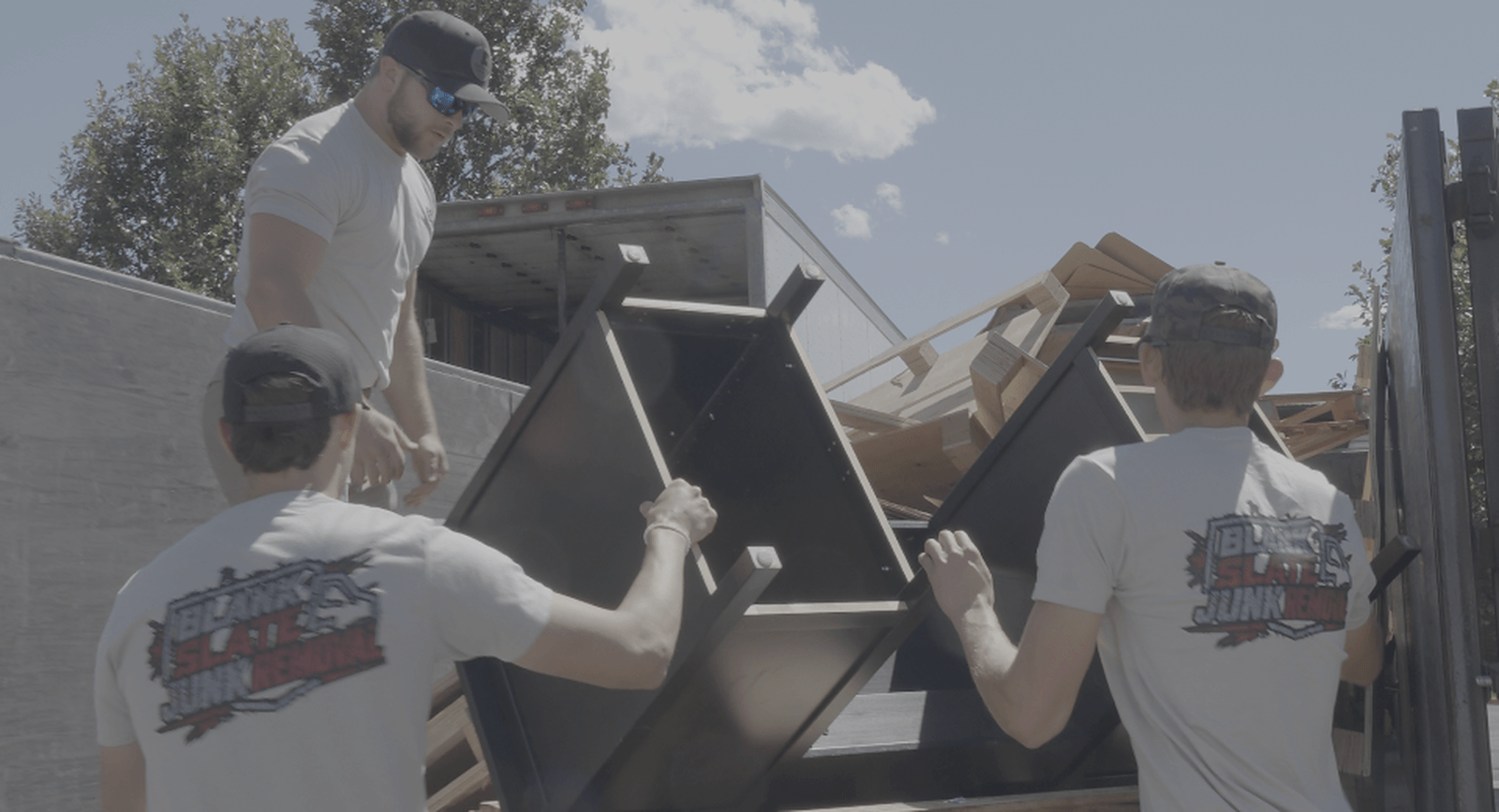 Blank Slate Junk Removal crew loading furniture into the dump trailer