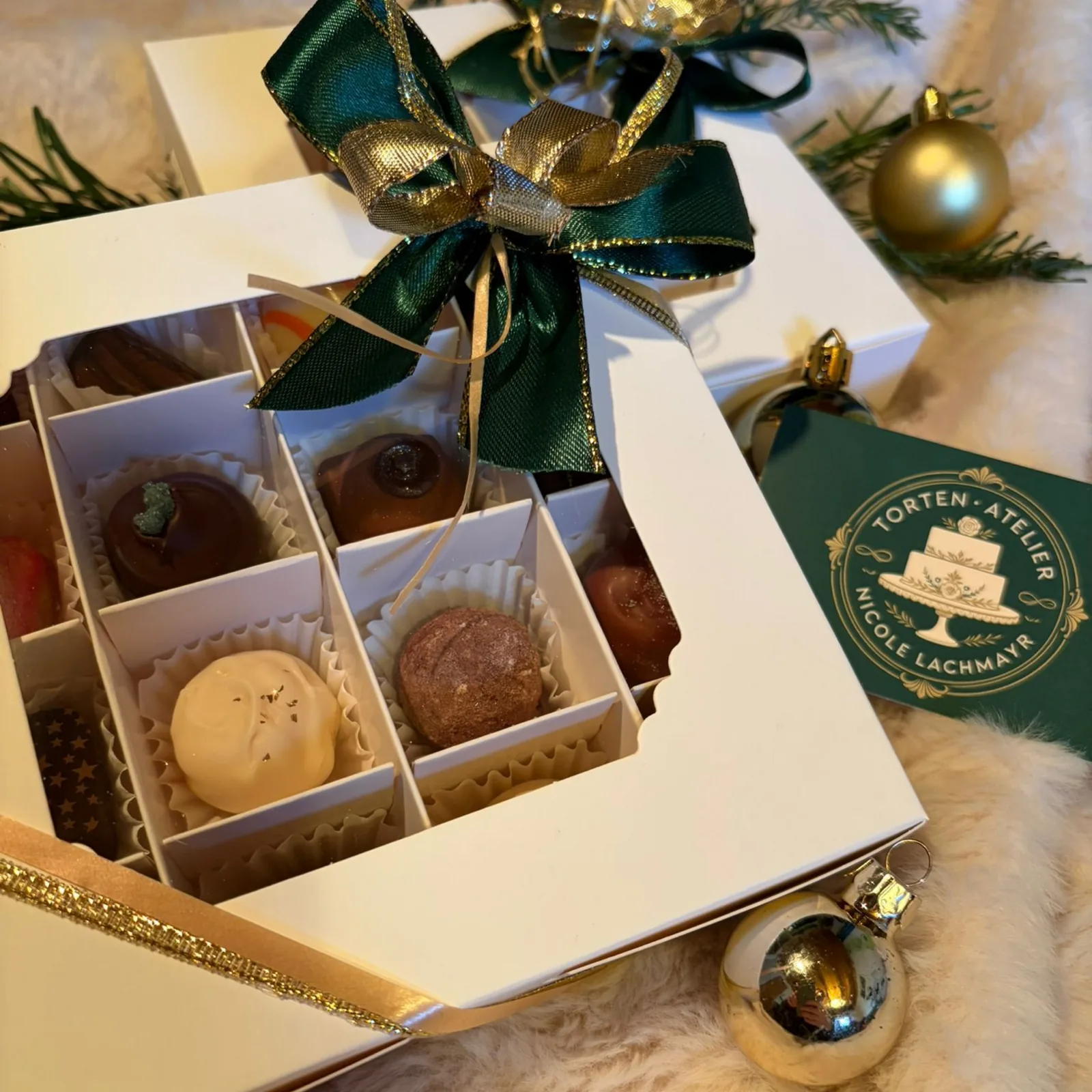Geschenkbox mit grünem Seidenband und Logo-Anhänger des Torten Ateliers