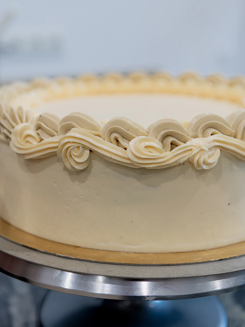 Nahaufnahme eines von Hand gespritzten Rosettenkranzes am oberen Rand einer Torte