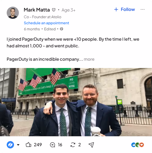 Two men in suits with green ties smiling and posing outside the New York Stock Exchange with flags above.