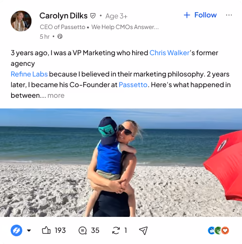 Woman wearing sunglasses holding child on a sandy beach with calm ocean and blue sky.