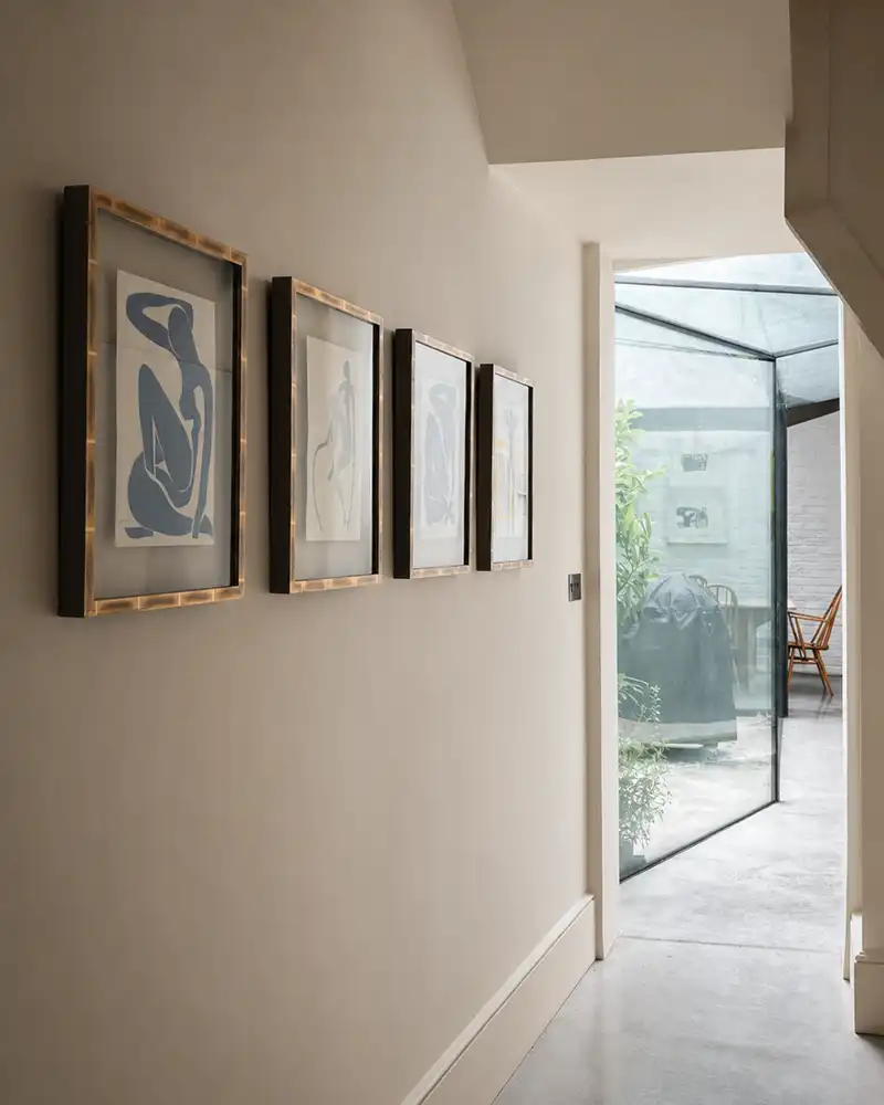 Hallway with four framed abstract figure prints on the wall and a glass door opening to a patio.