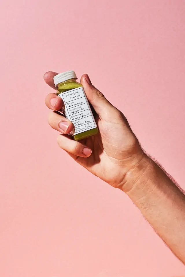 Een flesje met medicijn/supplement vastgehoudn in de hand