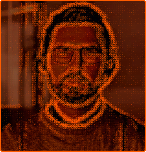 Portrait of a man with glasses, a beard, and dark hair against a blurred background.