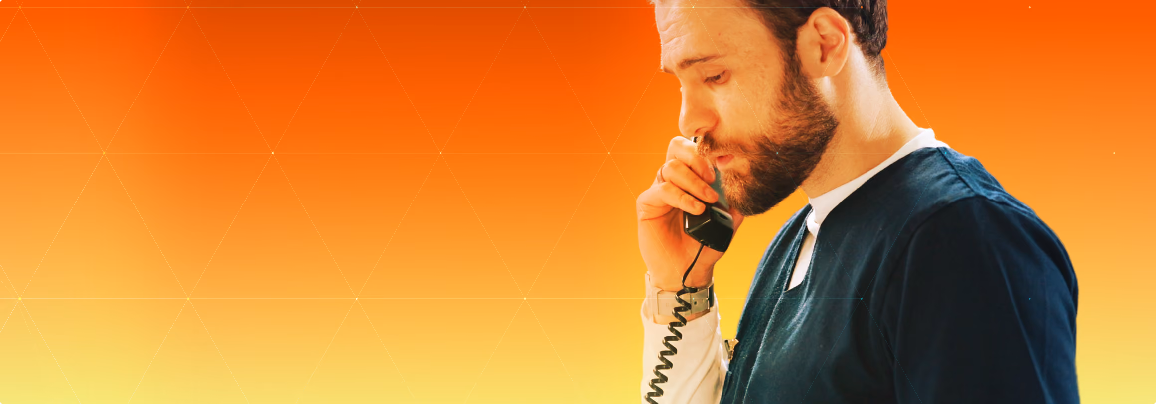 Bearded man in dark scrubs speaking on a corded telephone against a gradient orange to yellow background with faint geometric lines.