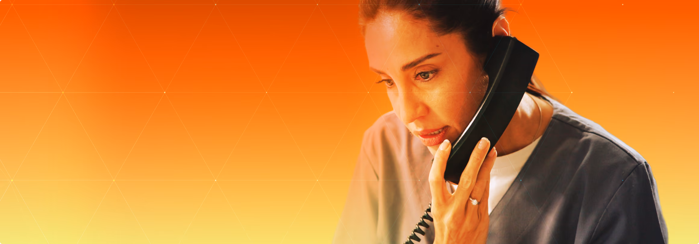 Woman in medical scrubs holding a black corded phone handset to her ear, appearing focused and engaged in conversation, with an orange to yellow gradient background.