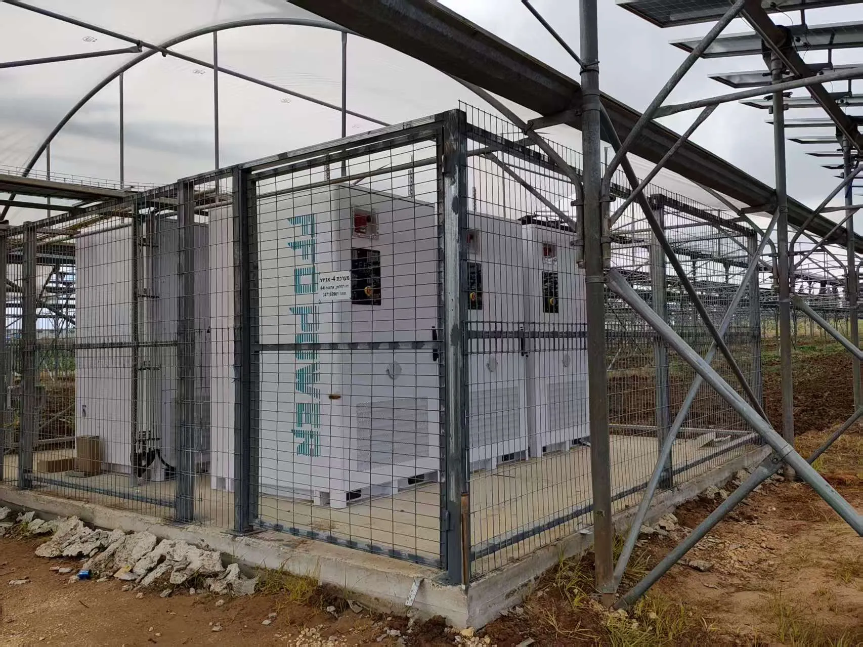 FFD POWER Batterieschränke in einem umzäunten Sicherheitsbereich unter einer Gewächshaus-Solaranlage in Israel